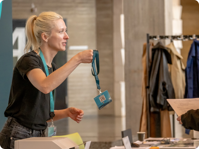 Woman at a check-in stand handing out a badge